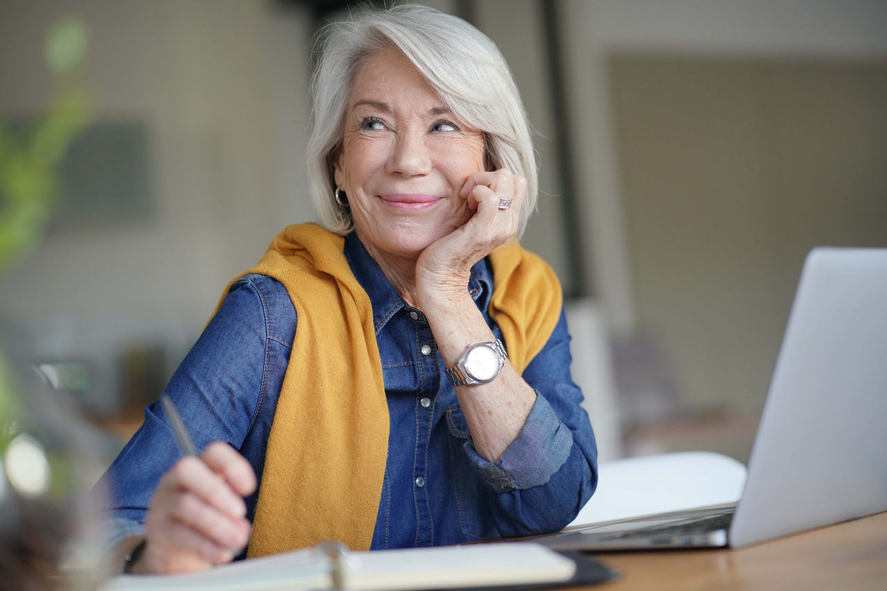  Fresh looking senior woman thinking and working from home                              