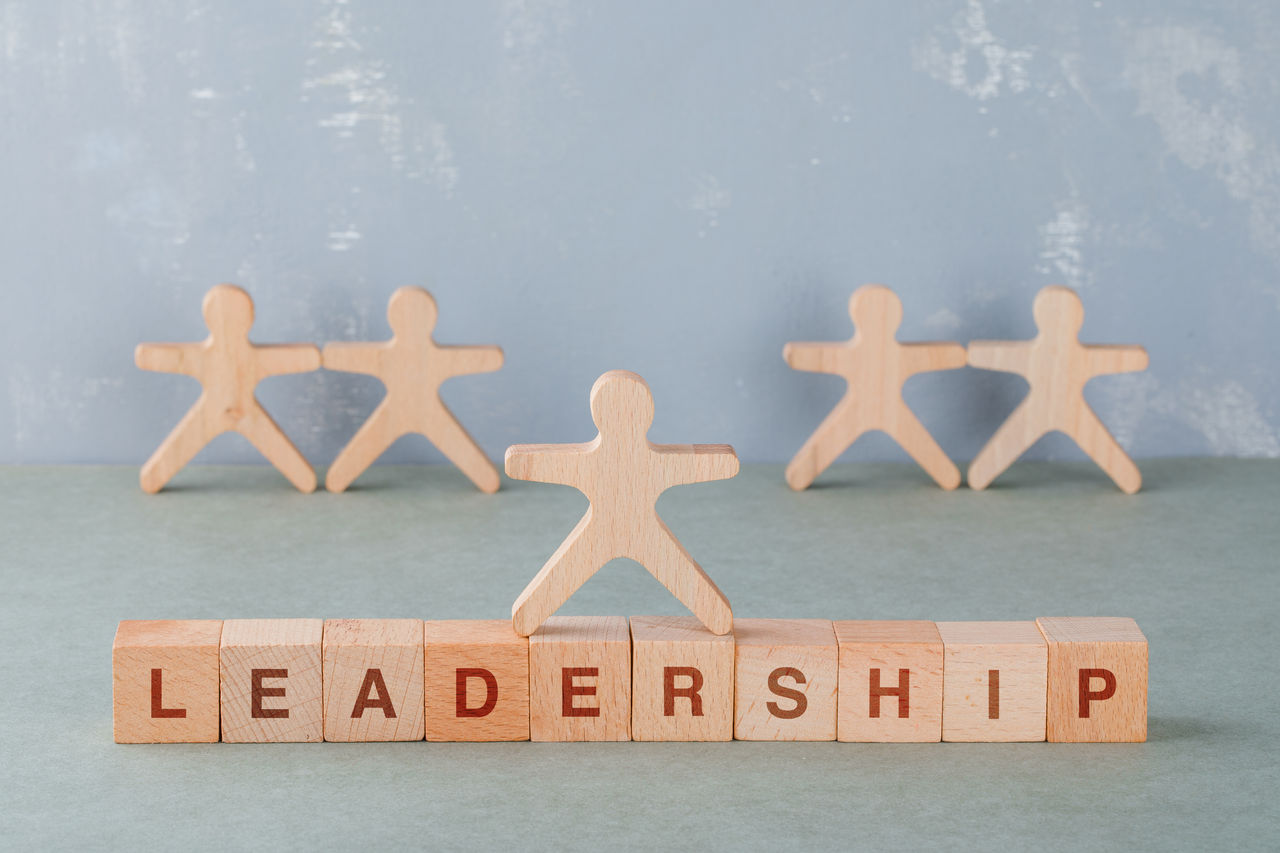 Team building and business concept with wooden blocks with words on it, wooden human figures on sage color background side view. horizontal image 